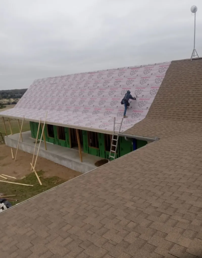 Worker preparing underlayment for a metal roof installation in Shelby